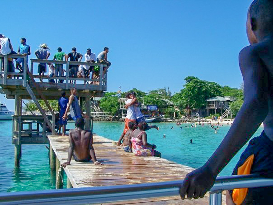 locals in West Bay playing and jumping off the pier in Roatan, Honduras