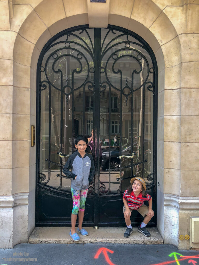 Short, glass door with black iron details in Paris. This picture with my children was taken in 7th arrondissement neighbourhood in Paris, France