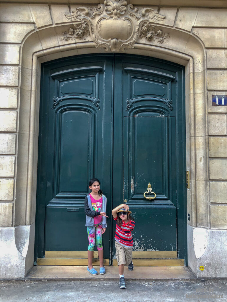 Short, green, wooden door without windows in Paris. This picture with my children was taken in 7th arrondissement neighbourhood in Paris, France
