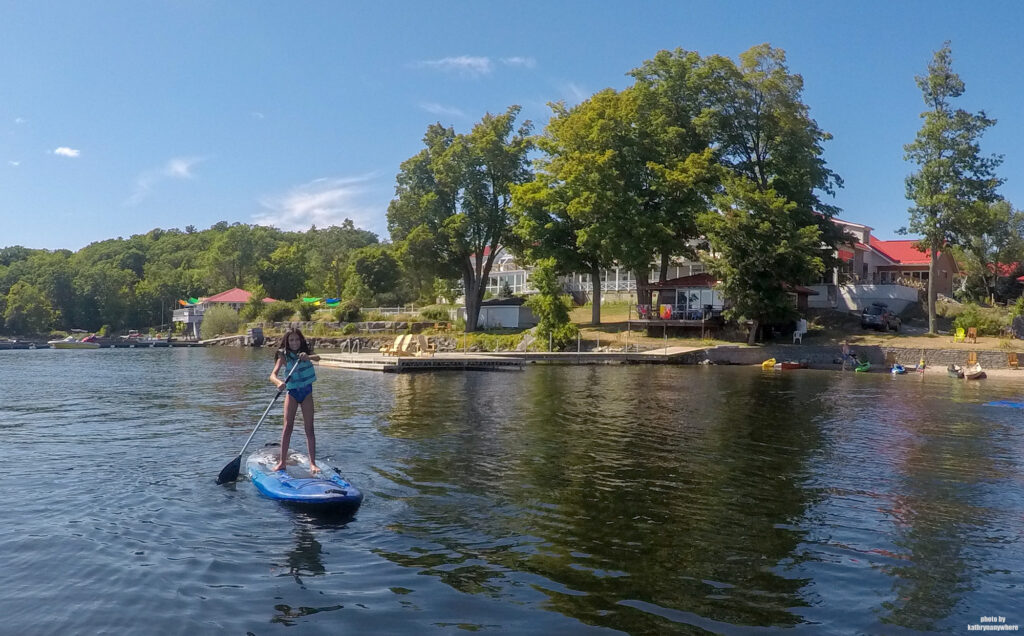 My daughter on a stand up paddleboard SUP on Stoney Lake in front of Viamede Resort