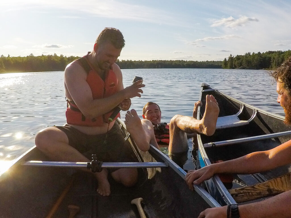 Chris Mitchell from Traveling Mitch hanging precariously between two canoes
