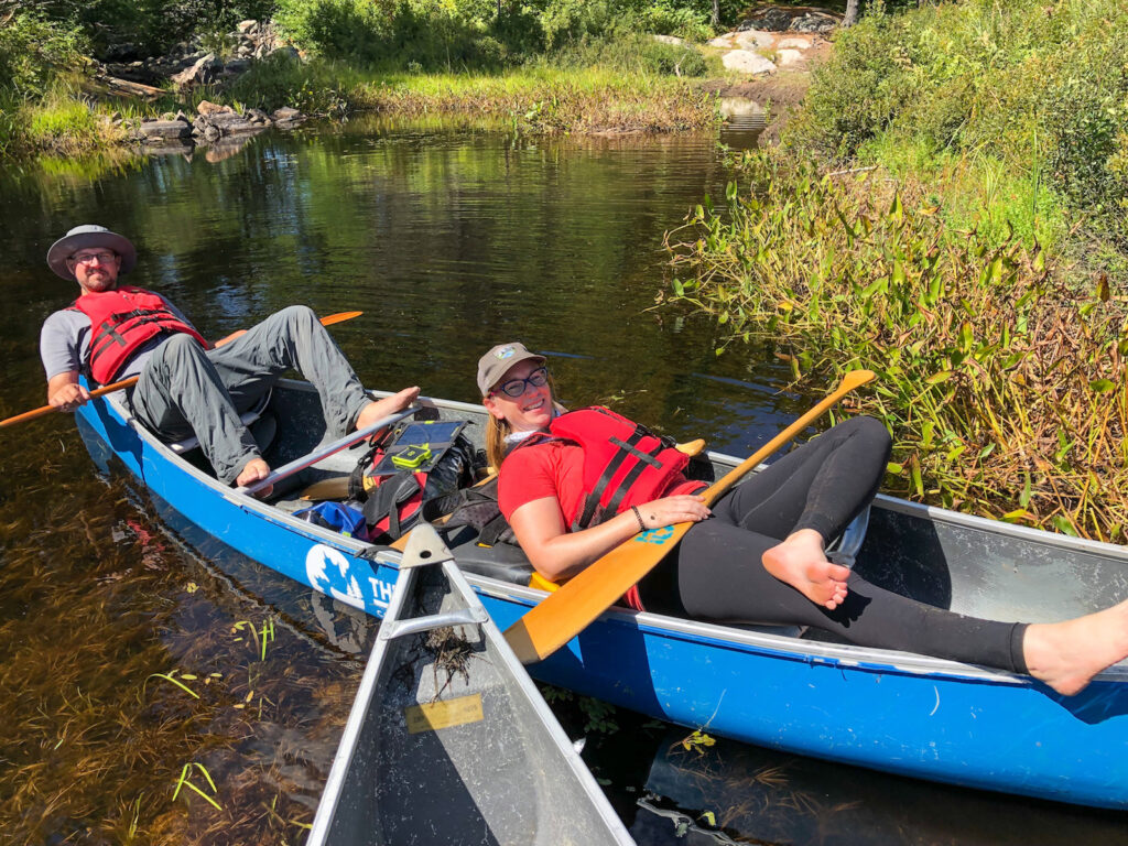 Kevin from The Wandering Wagars and Kathryn from KathrynAnywhere relaxing during a canoe portage with friends in Kawartha highlands Provincial Park