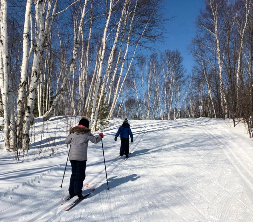 Sudbury Winter Activities - kids heading up a small hill while cross country skiing in Kivi Park in Sudbury