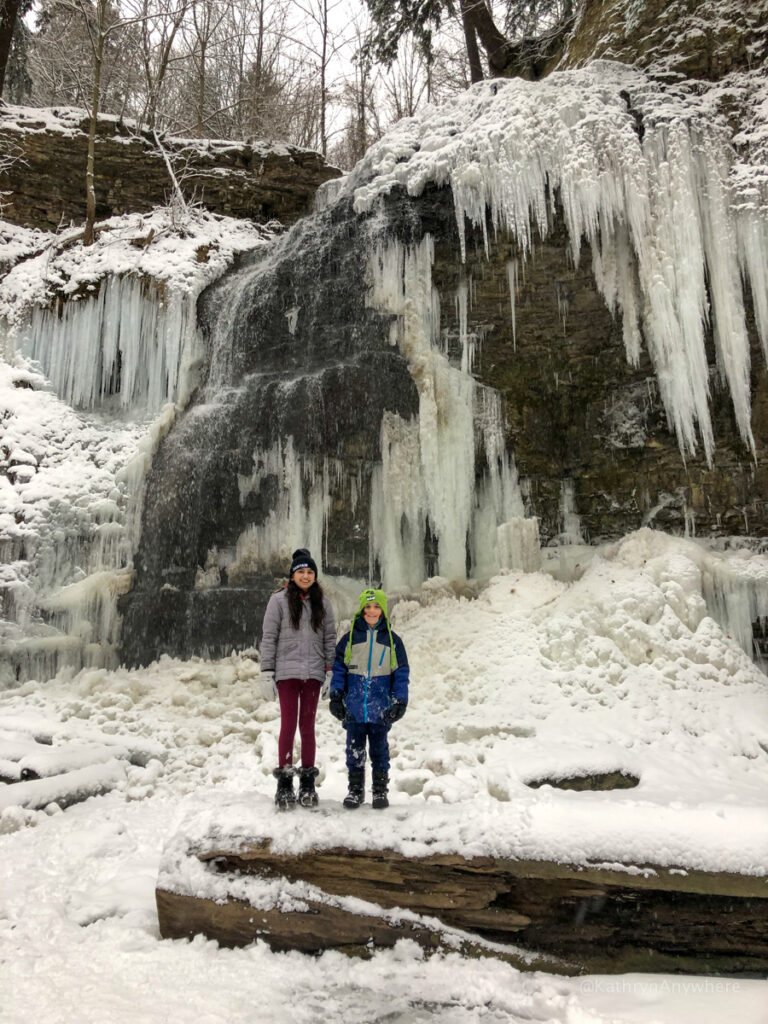 Tiffany Falls Ancaster Hamilton Ontario frozen in winter with two kids standing in front of it