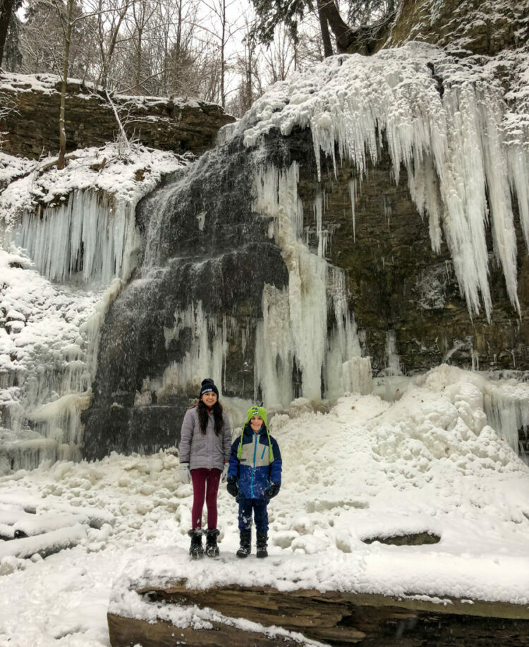 Tiffany Falls Ancaster Hamilton Ontario frozen in winter with two kids standing in front of it