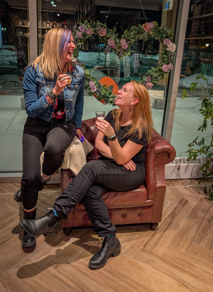 Girls getaway in Lanaudière-Mauricie, Authentic Quebec Trois-Rivières best girls getaway in Quebec, Kat and Lindsay posing in Mariana Distillery with glassesPhoto by Lindsay Davies / IveBeenBit.ca 